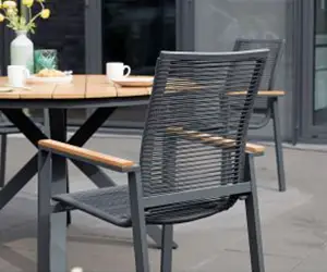 Ein moderner Stuhl steht neben einem Holztisch auf einer Terrasse.