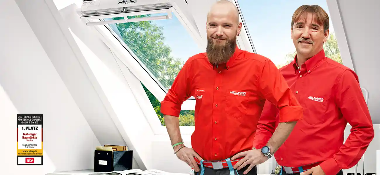 Zwei Hellweg Mitarbeiter lächeln in einem hellen Raum mit großem Dachfenster.