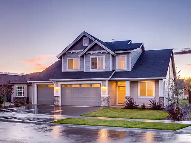 Ein Haus bei Abenddämmerung und regennasser Straße.