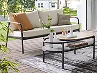 Ein Sofa mit Kissen steht auf einer Terrasse neben einem Tisch mit Dekorationen.