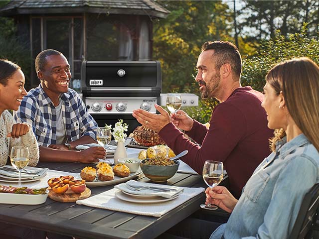 Weber Menschen am Esstisch beim Grillen draußen