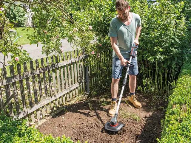 Ein Mann bedient in einem sonnigen Garten ein AL-KO Gerät zur Bodenbearbeitung.