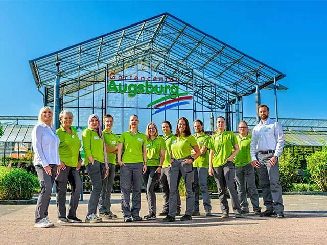 Eine Gruppe von Mitarbeitern steht vor dem Gartencenter Augsburg.