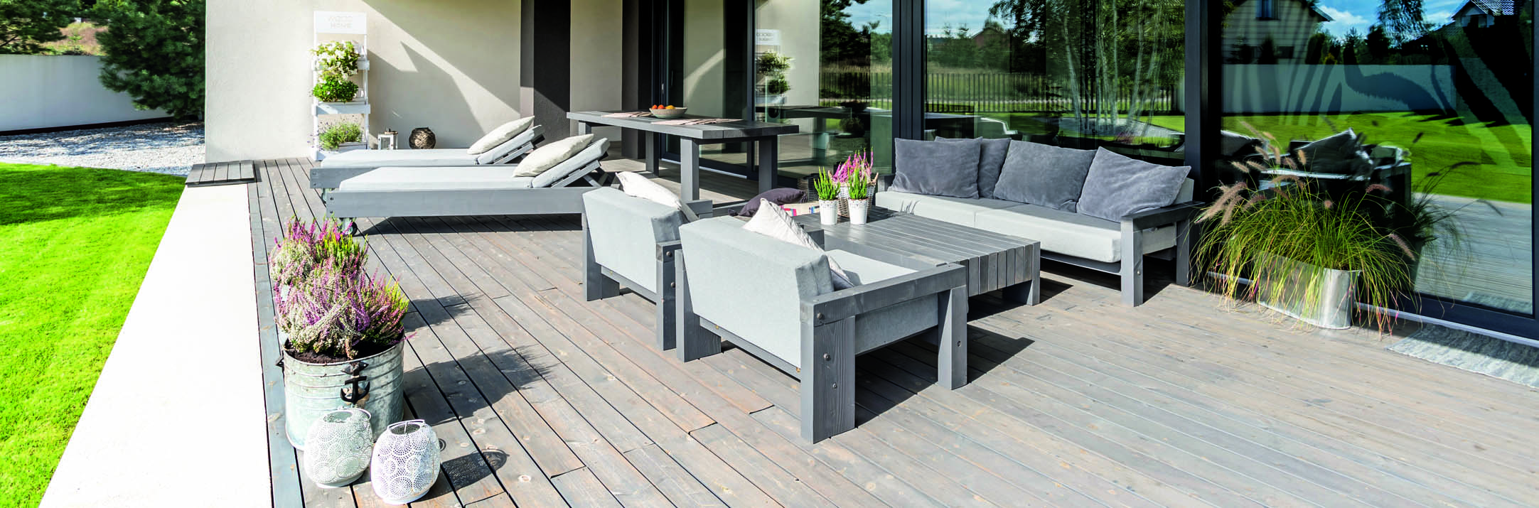 Holzterrasse mit Gartenmöbeln in grau und Blumen