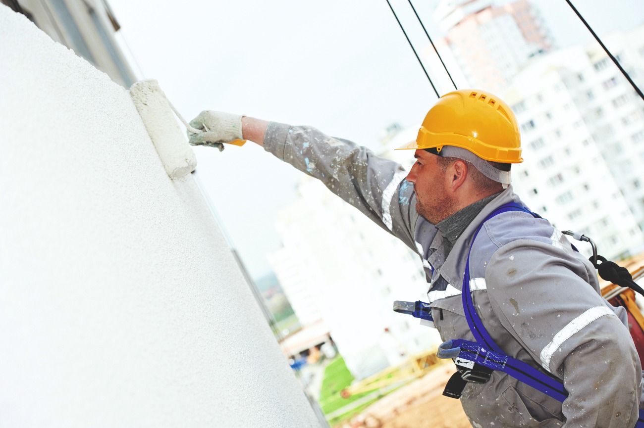 Ein Mann der die Außenfassade weiß streicht