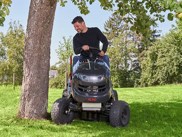 Ein Mann mäht den Rasen mit einem Rasenmähertraktor von AL-KO.