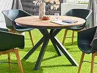 Ein runder Holztisch steht mit vier Stühlen auf einem grünen Teppich in einem modernen Raum.