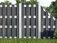 Ein schwarzer Gartenzaun mit geometrischen Mustern steht vor grünen Bäumen und Sträuchern.