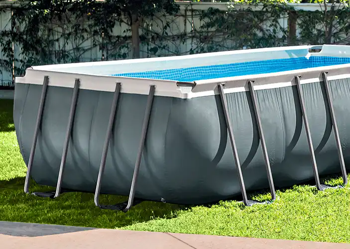 Ein rechteckiger Pool steht stabil auf einem Rasen, gestützt von Metallstreben im Garten.