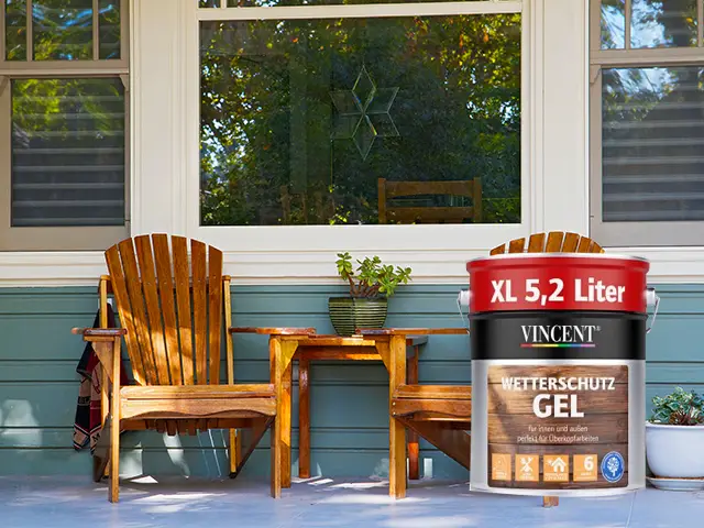 Ein kleiner Tisch und zwei Holzstühle stehen auf einer Veranda.