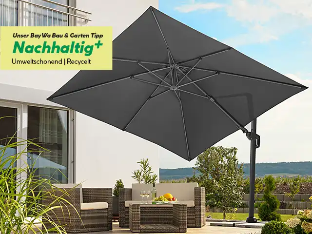 Ein großer, grauer Sonnenschirm steht geöffnet auf einer Terrasse neben einem Gartenmöbel-Set.