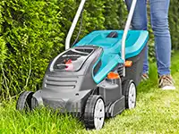 Eine Person mäht den Rasen mit einem Gardena Rasenmäher.
