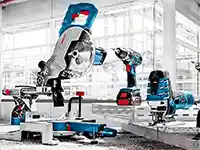 Eine Kappsäge und Bohrmaschine stehen in einer hellen Werkstatt mit großen Fenstern.