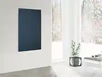 Eine Infrarotheizung hängt an einer weißen Wand in einem modernen, minimalistisch eingerichteten Raum.