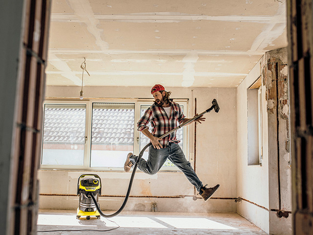 Mann mit Industriestaubsauger im Rohbau