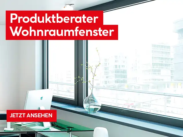 Ein Schreibtisch vor großen Fenstern zeigt einen Computer und eine Vase.