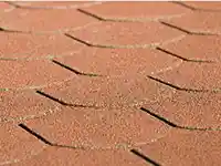 Rote Schindeln bedecken gleichmäßig ein Dach und sind in engem Muster verlegt.