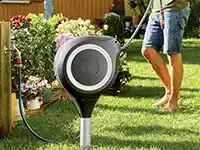 Ein Gartenschlauch wird aus einer automatischen Schlauchtrommel ausgerollt.