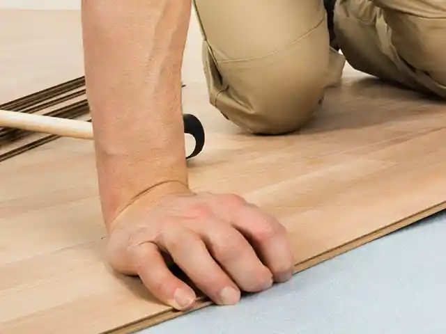 Eine Person verlegt einen Laminatboden.