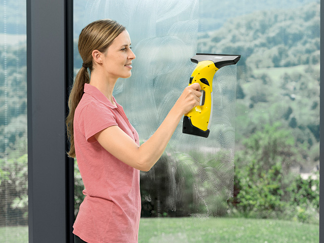 Frau mit Kärcher Fenstersauger beim Fensterputzen