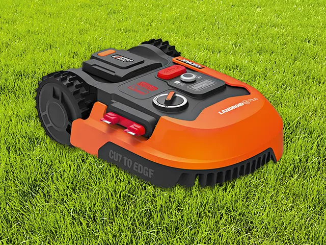 Ein orange-schwarzer Mähroboter von Landroid fährt über Gras.