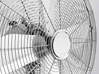 Ein Metallventilator dreht sich langsam in einem hell erleuchteten Raum.