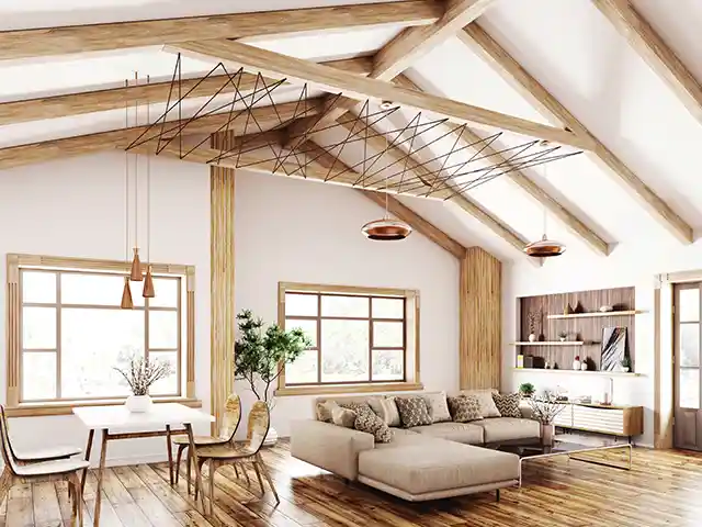 Ein gemütliches Wohnzimmer mit Holzdecke, beiger Couch und großem Esstisch in heller Atmosphäre.