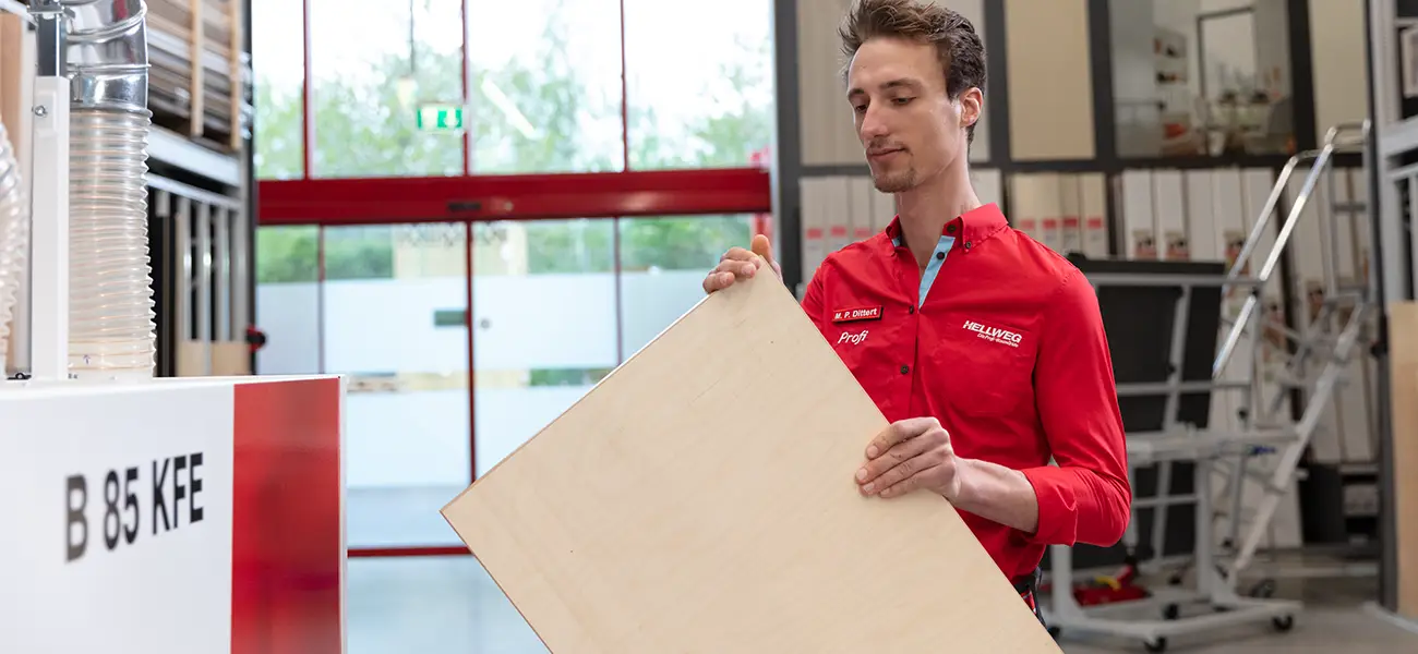 Mitarbeiter mit Holzplatte vor CNC Säge