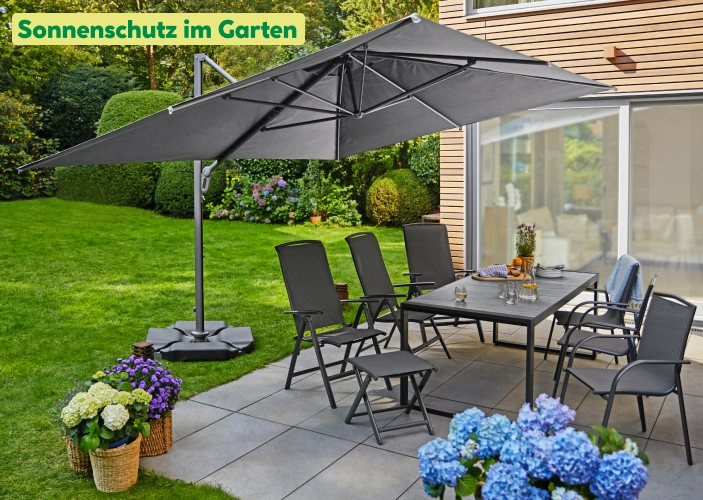 Grauer Ampelschirm über einer Sitzgruppe in einem Garten