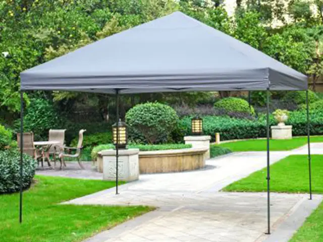 Ein Pavillon steht in einem parkähnlichen Garten neben einer gefliesten Terrasse mit Gartenmöbeln