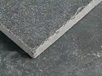 Eine graue Steinplatte liegt auf einem weiteren Steinboden und zeigt eine raue Textur.