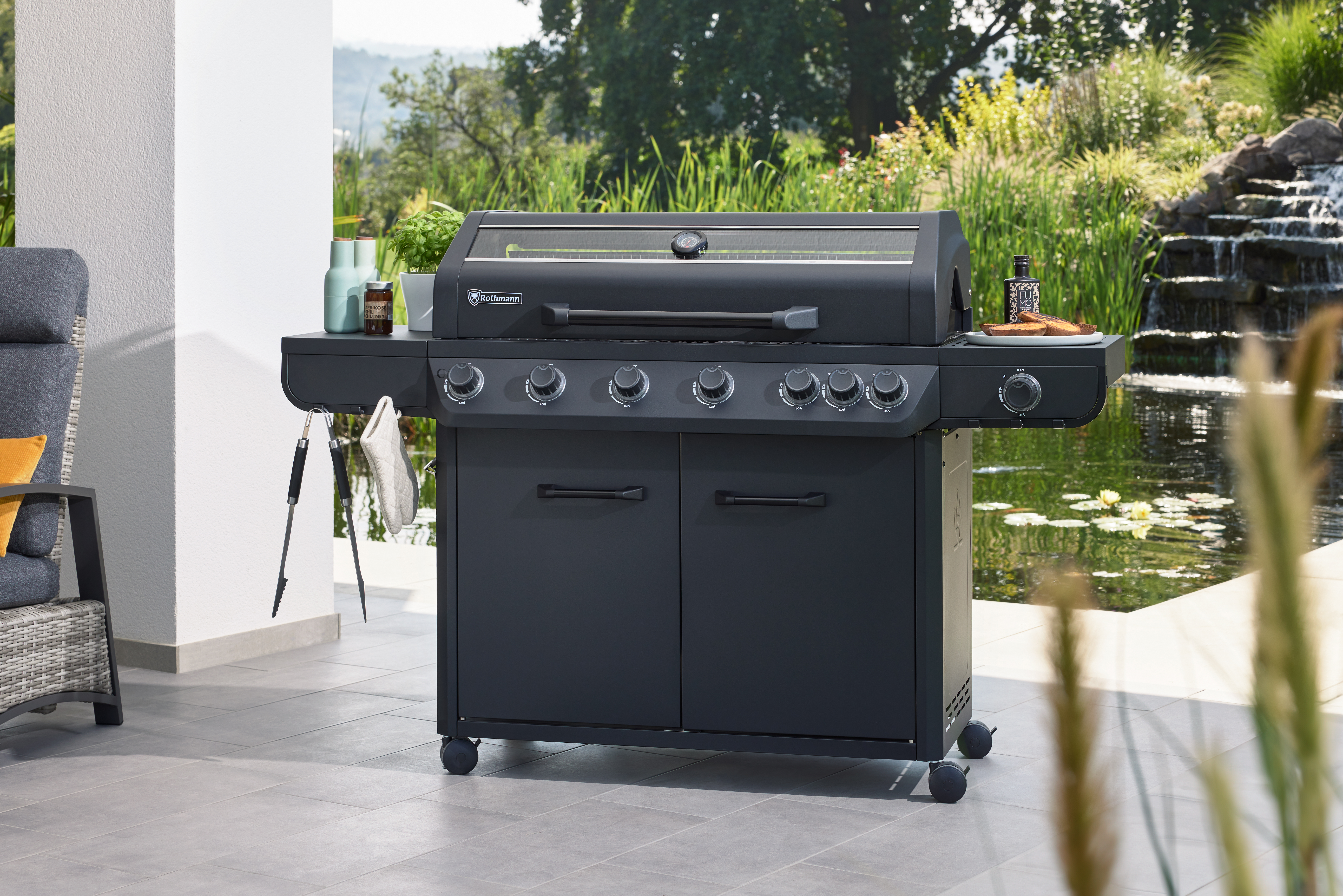 Moderner Gasgrill von Rothmann mit mehreren Brennern und großzügigen Ablageflächen auf der Terrasse, ideal für entspanntes Grillen im Garten.