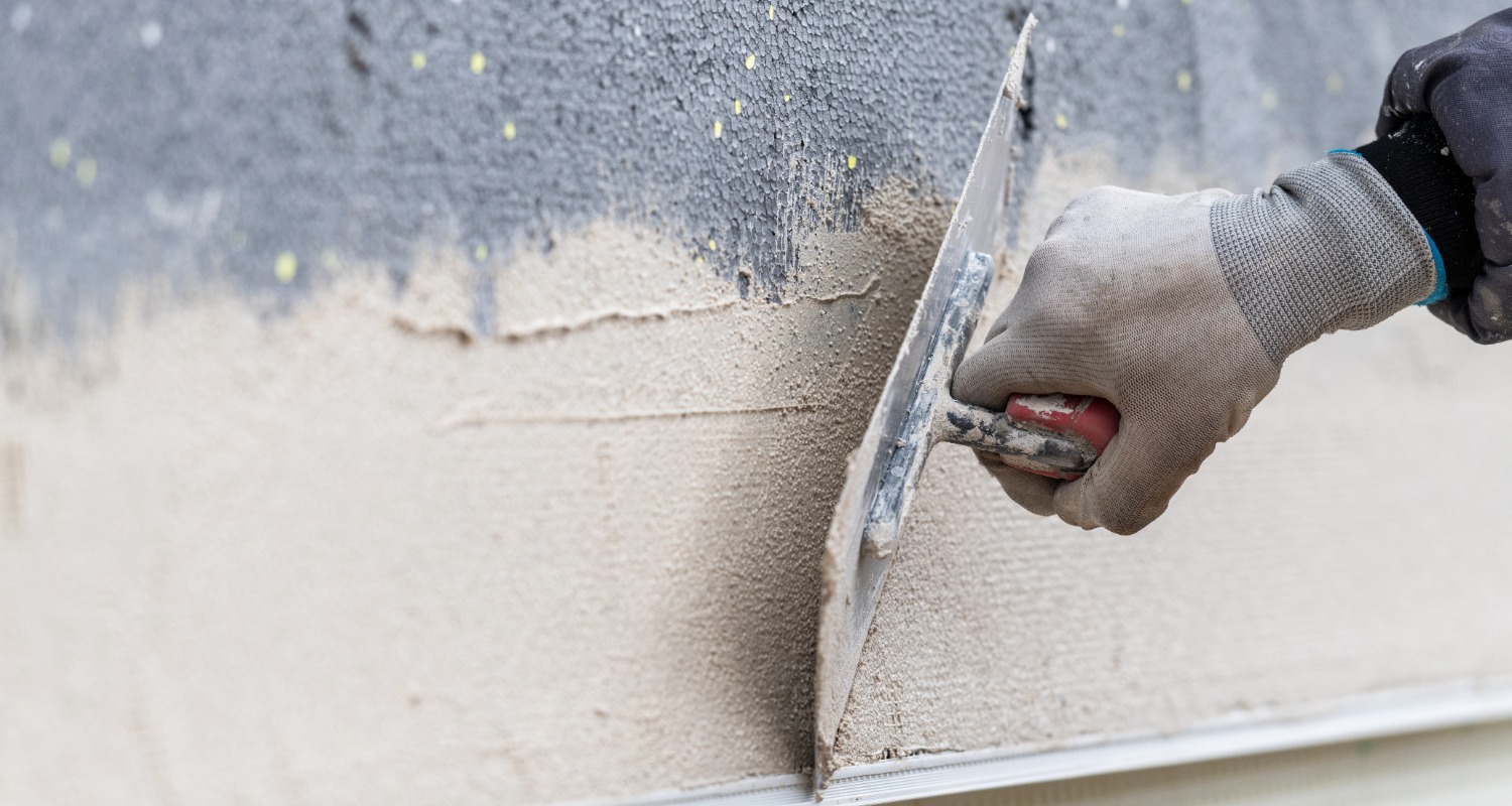 Ein Mann der eine Außenwand verputzt