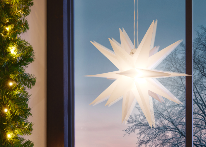 Sternförmige Beleuchtung hängt an Scheibe