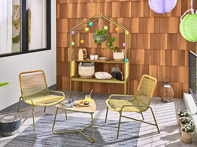 Zwei Stühle und ein Tisch stehen auf einem Teppich in einem gemütlichen Balkonbereich.