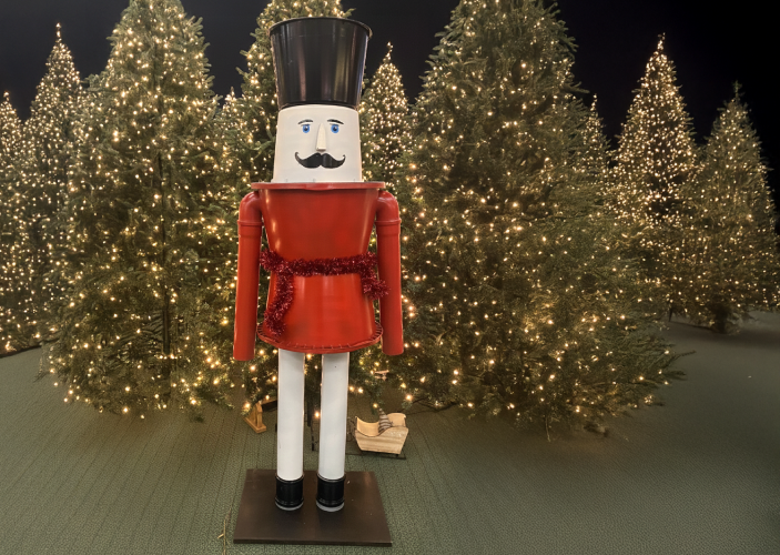 Nussknacker der vor beleuchteten Weihnachtsbäumen steht
