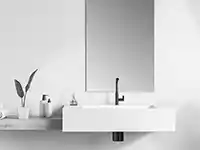 Ein Waschbecken mit Wasserhahn steht in einem minimalistischen Badezimmer neben Pflanzen und Seifenspender.