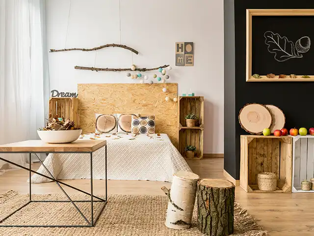Ein Schlafzimmer mit einem Holzbett, dekoriert mit Naturmotiven und einem Tisch aus Holz und Metall.