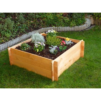 Ein Hochbeet aus Holz mit blühenden Pflanzen steht auf einem Rasen im Garten.