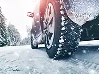 Ein Auto fährt auf einer schneebedeckten Straße, umgeben von schneebedeckten Bäumen.