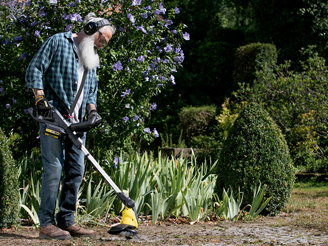 Mann mit Akku Trimmer im Garten