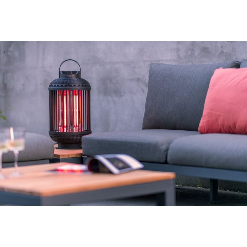 Ein Elektroheizstrahler der zwischen den Gartenmöbeln auf einem Tisch stehen