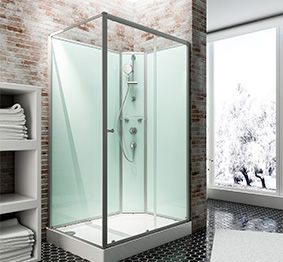 Eine moderne Duschkabine steht in einem Badezimmer mit Backsteinwand und großen Fenstern.