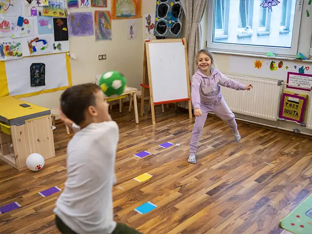 Ein Junge und ein Mädchen spielen mit einem Ball im Kinderzimmer.