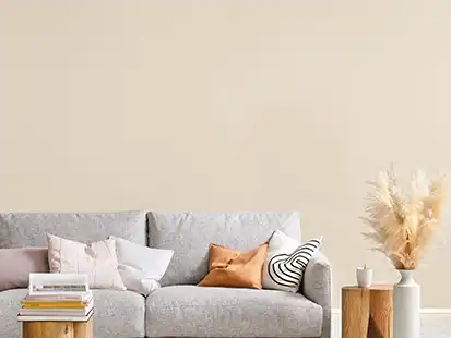 Ein graues Sofa mit Kissen steht in einem minimalistischen Wohnzimmer neben einem Beistelltisch.