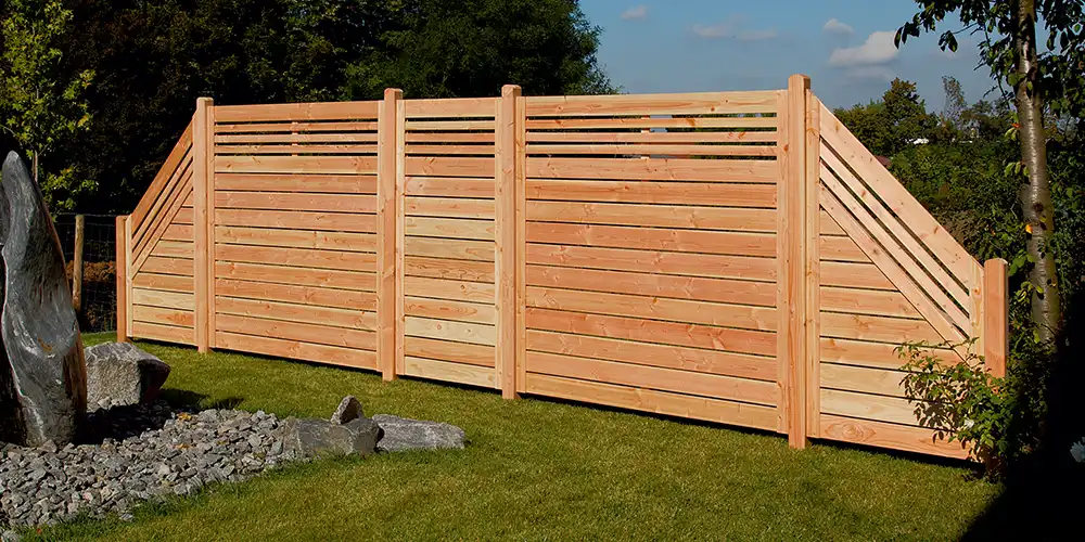 Ein hoher, hölzerner Sichtschutzzaun in einem Garten.