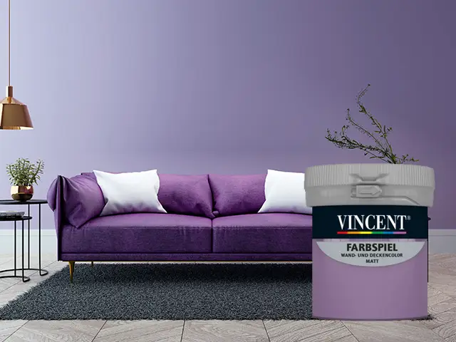 Ein lilafarbener Eimer Farbe steht vor einem stilvollen Wohnzimmer mit violettem Sofa.