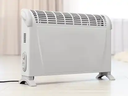 Ein weißer elektrischer Heizkörper steht auf dem Boden in einem hellen Raum.