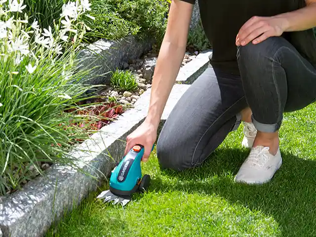 Frau schneidet Rasenkanten mit Akku Gartenschere