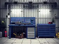 Eine blaue Werkbank mit Werkzeugen steht in einer Garage neben einem Werkzeugkasten.
